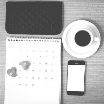 office desk : coffee with phone,calendar,wallet,heart on wood background black and white color