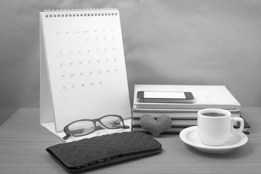 desktop : coffee with phone,stack of book,wallet,heart,eyeglasses,calendar on wood background black and white color