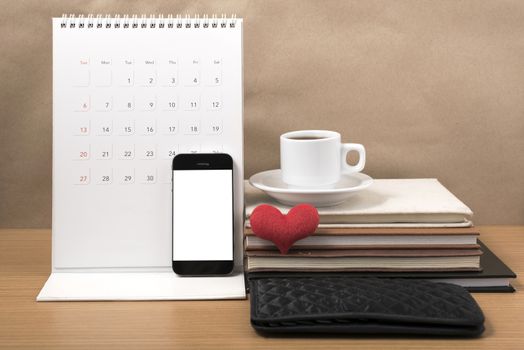 office desk : coffee with phone,wallet,calendar,heart,stack of book on wood background