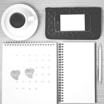 office desk : coffee with phone,wallet,calendar,heart,notepad on wood background black and white color