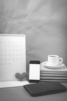 office desk : coffee with phone,wallet,calendar,heart,stack of book on wood background black and white color