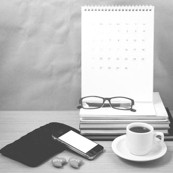 office desk : coffee with phone,wallet,calendar,heart,stack of book,eyeglasses on wood background black and white color