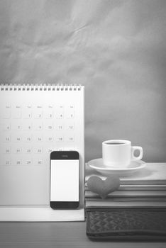 office desk : coffee with phone,wallet,calendar,heart,stack of book on wood background black and white color