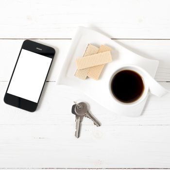 coffee cup with wafer,phone,key on white wood background