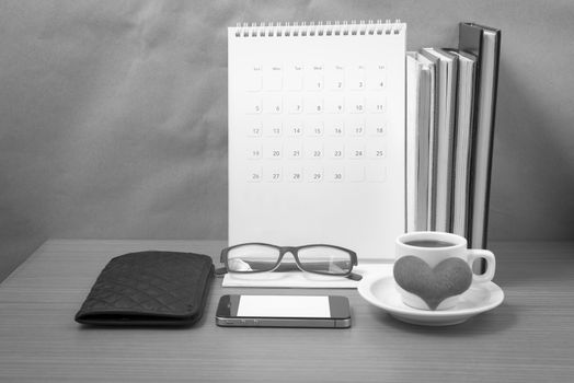 desktop : coffee with phone,stack of book,wallet,heart,eyeglasses,calendar on wood background black and white color