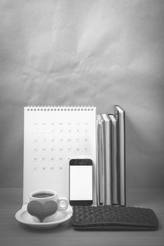 office desk : coffee with phone,wallet,calendar,heart,stack of book on wood background black and white color