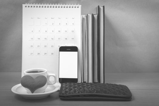 office desk : coffee with phone,wallet,calendar,heart,stack of book on wood background black and white color