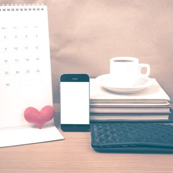 office desk : coffee with phone,wallet,calendar,heart,stack of book on wood background vintage style