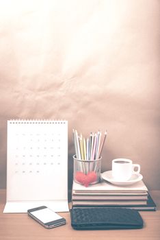 office desk : coffee with phone,wallet,calendar,heart,color pencil box,stack of book,heart on wood background vintage style