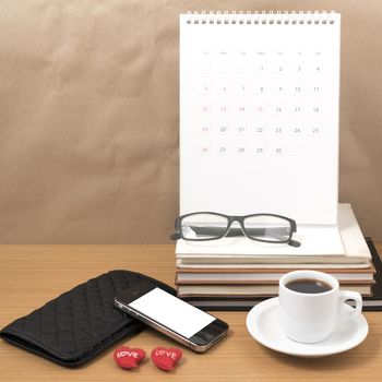 office desk : coffee with phone,wallet,calendar,heart,stack of book,eyeglasses on wood background