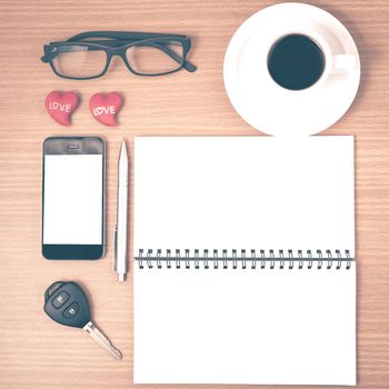 office desk : coffee and phone with car key,eyeglasses,notepad,heart on wood background vintage style