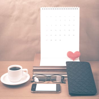 office desk : coffee with phone,stack of book,eyeglasses,wallet,calendar,heart on wood background vintage style