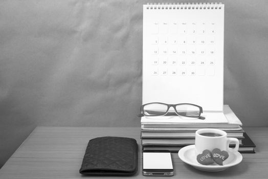 office desk : coffee with phone,wallet,calendar,heart,stack of book,eyeglasses on wood background black and white color