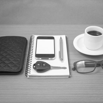 coffee and phone with notepad,car key,eyeglasses and wallet on wood table background black and white color