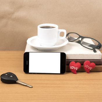 office desk : coffee and phone with car key,eyeglasses,stack of book,heart on wood background