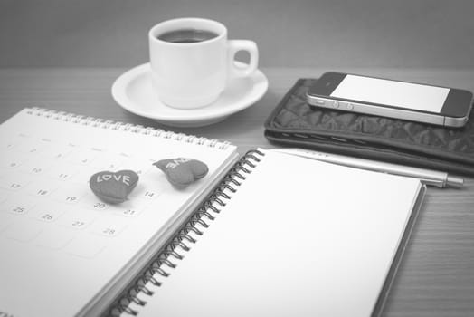 office desk : coffee with phone,wallet,calendar,heart,notepad on wood background black and white color