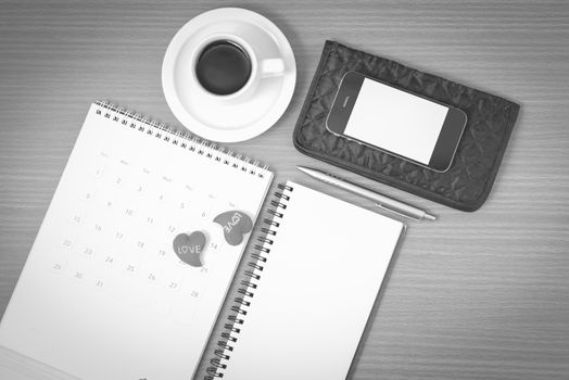 office desk : coffee with phone,wallet,calendar,heart,notepad on wood background black and white color