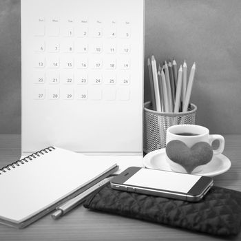 office desk : coffee with phone,wallet,calendar,heart,color pencil box,notepad,heart on wood background black and white color