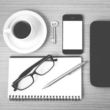 coffee and phone with notepad,key,eyeglasses and wallet on wood table background black and white color