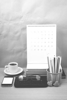 office desk : coffee with phone,wallet,calendar,color pencil box,stack of book,heart,eyeglasses on wood background black and white color