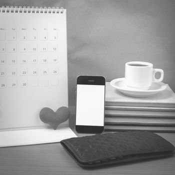 office desk : coffee with phone,wallet,calendar,heart,stack of book on wood background black and white color