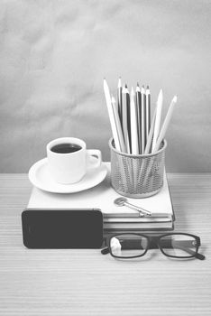 office desk : coffee and phone with key,eyeglasses,stack of book,pencil box black and white color