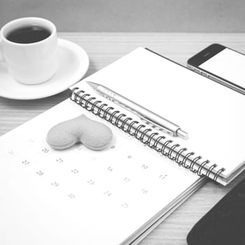 office desk : coffee with phone,wallet,calendar,heart,notepad on wood background black and white color