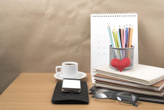 office desk : coffee with phone,wallet,calendar,color pencil box,stack of book,heart,eyeglasses on wood background