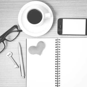 office desk : coffee and phone with key,eyeglasses,notepad,heart on wood background black and white color