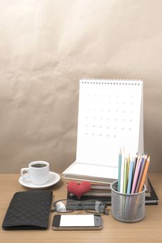 office desk : coffee with phone,wallet,calendar,color pencil box,stack of book,heart,eyeglasses on wood background