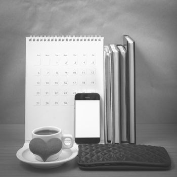 office desk : coffee with phone,wallet,calendar,heart,stack of book on wood background black and white color