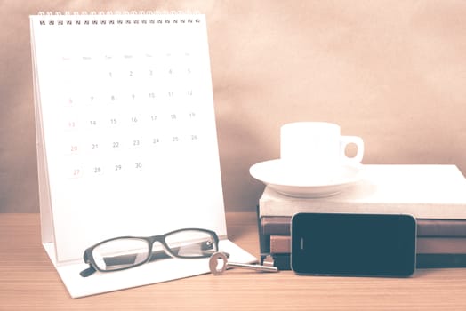 coffee and phone with key,eyeglasses,stack of book,calendar on wood background vintage style