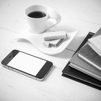 coffee cup with wafer,phone,stack of book on white wood background black and white color