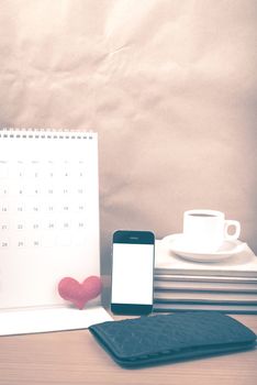 office desk : coffee with phone,wallet,calendar,heart,stack of book on wood background vintage style