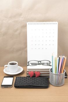 office desk : coffee with phone,wallet,calendar,color pencil box,stack of book,heart,eyeglasses on wood background