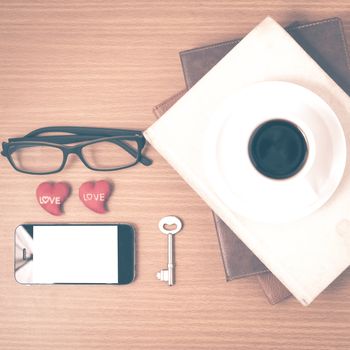 office desk : coffee and phone with key,eyeglasses,stack of book,heart on wood background vintage style