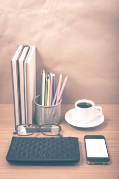 office desk : coffee with phone,stack of book,eyeglasses,wallet,color pencil box on wood background vintage style