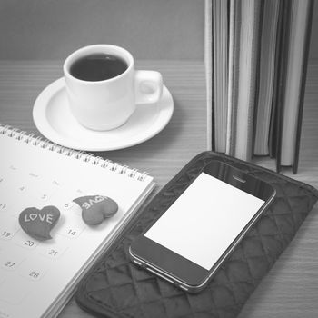 office desk : coffee with phone,wallet,calendar,heart,stack of book on wood background black and white color