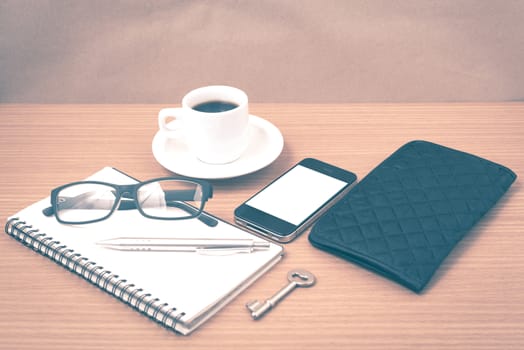 coffee and phone with notepad,key,eyeglasses and wallet on wood table background vintage style