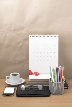 office desk : coffee with phone,wallet,calendar,color pencil box,stack of book,heart,eyeglasses on wood background