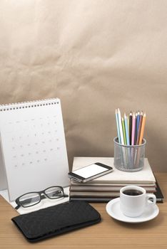 office desk : coffee with phone,wallet,calendar,color pencil box,stack of book,eyeglasses on wood background