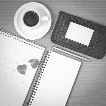 office desk : coffee with phone,wallet,calendar,heart,notepad on wood background black and white color