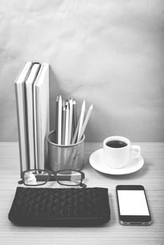 office desk : coffee with phone,stack of book,eyeglasses,wallet,color pencil box on wood background black and white color