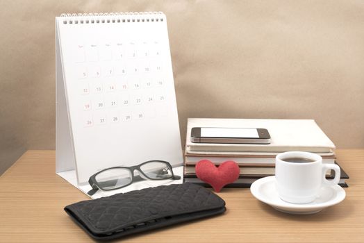 desktop : coffee with phone,stack of book,wallet,heart,eyeglasses,calendar on wood background