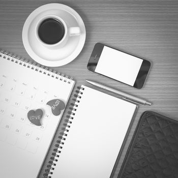 office desk : coffee with phone,wallet,calendar,heart,notepad on wood background black and white color