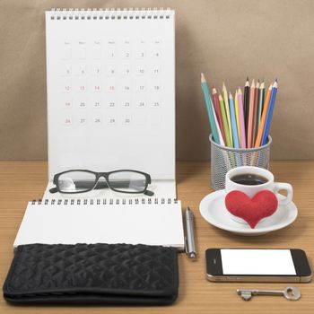 office desk : coffee with phone,wallet,calendar,heart,notepad,eyeglasses,color pencil box,key on wood background