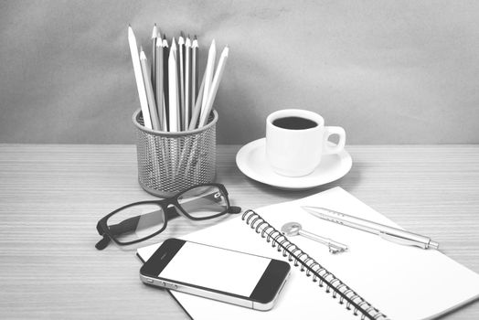 office desk : coffee and phone with key,eyeglasses,notepad,pencil box black and white color