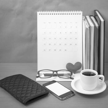 desktop : coffee with phone,stack of book,wallet,heart,eyeglasses,calendar on wood background black and white color