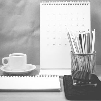 office desk : coffee with phone,wallet,calendar,color pencil box,notepad on wood background black and white color