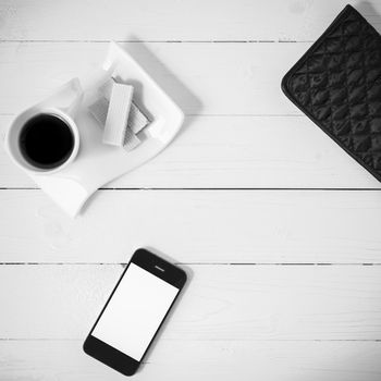 coffee cup with wafer,phone,wallet on white wood background black and white color
